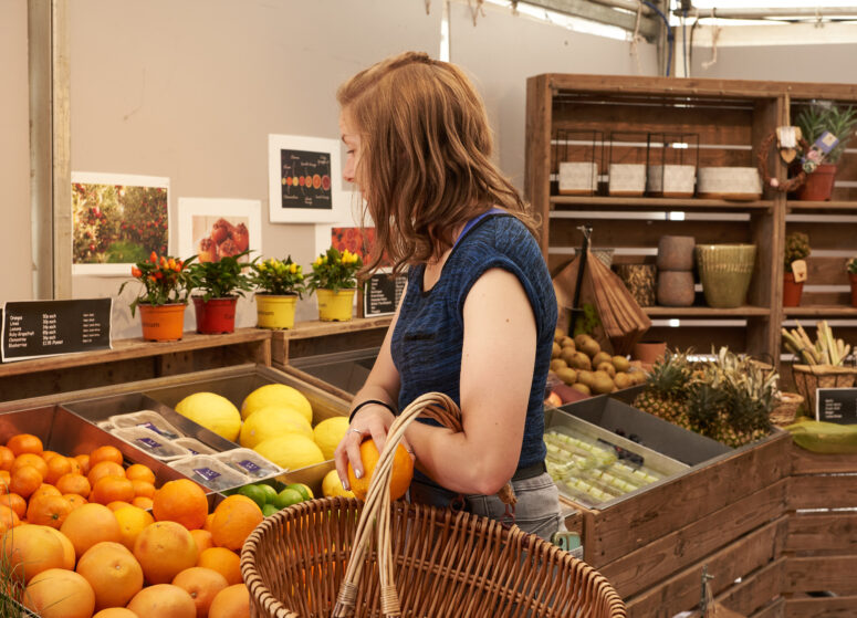 A customer shopping in front of oranges with a basket