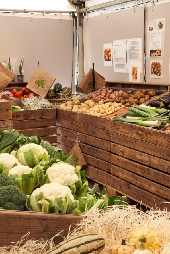 A wide shot of the veg marquee at The Balloon Tree - Wooden crates of carrots, cauliflowers, potatoes